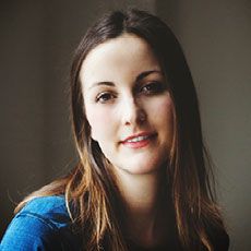 Portrait of a woman with long brown hair wearing a blue top in soft natural lighting