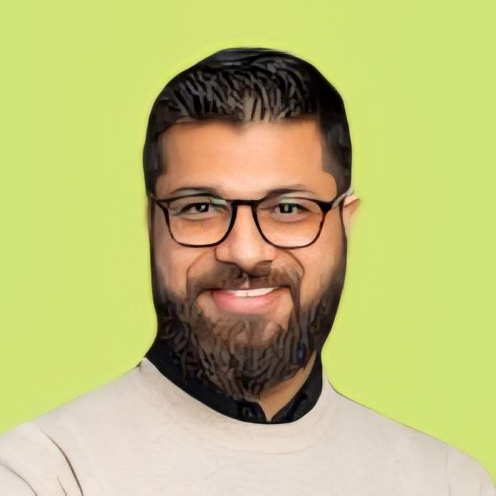 Portrait of a smiling man with glasses and a beard against a green background